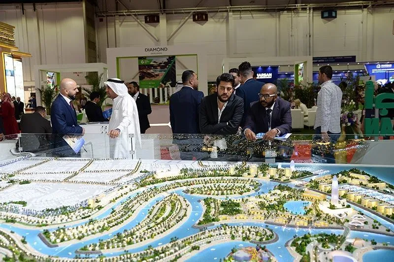 Investors and developers discussing projects at Dubai Property Show Australia 2026 real estate exhibition with a detailed Dubai property development model.